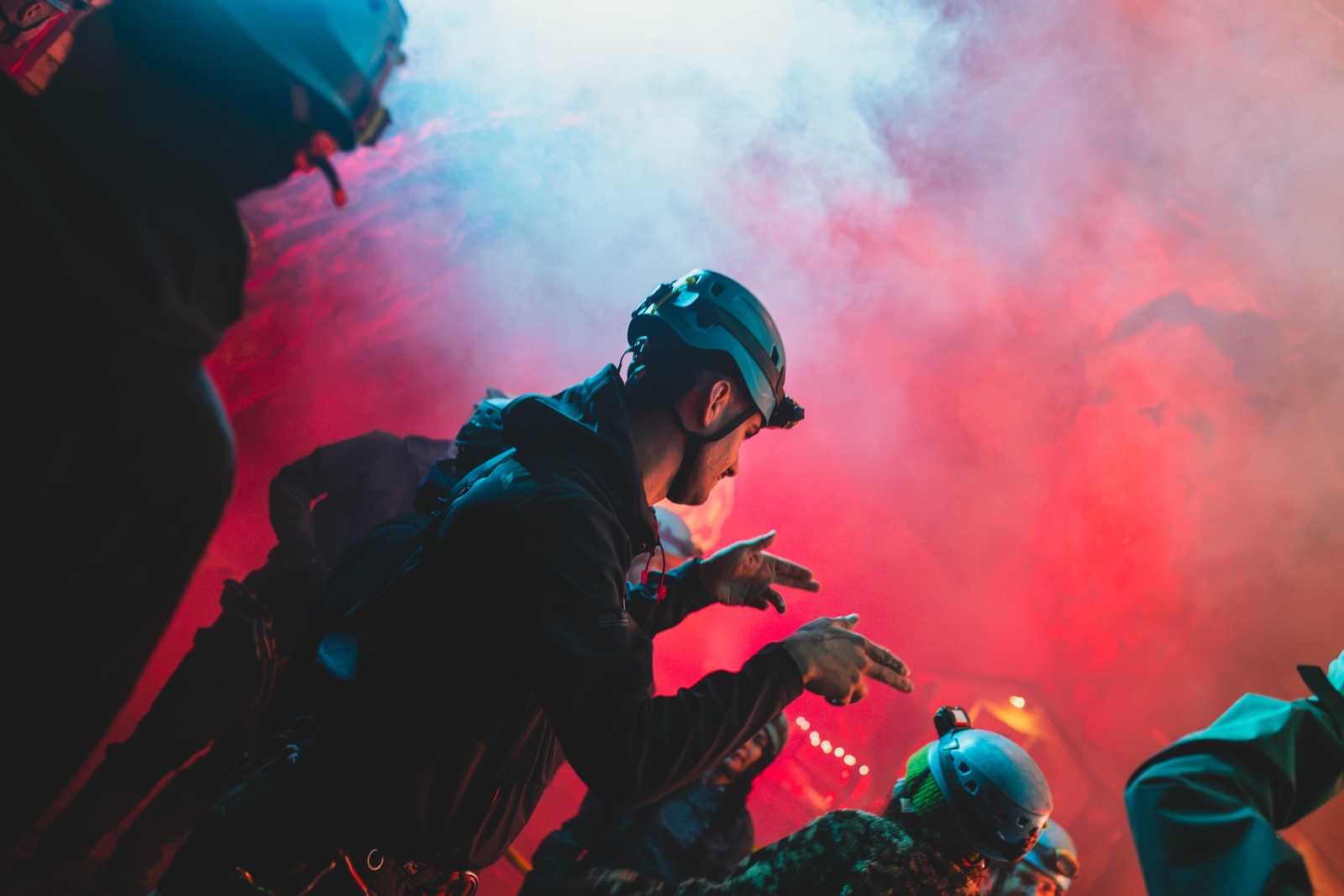 Ravers in helmets in red smoke in the chamber.
